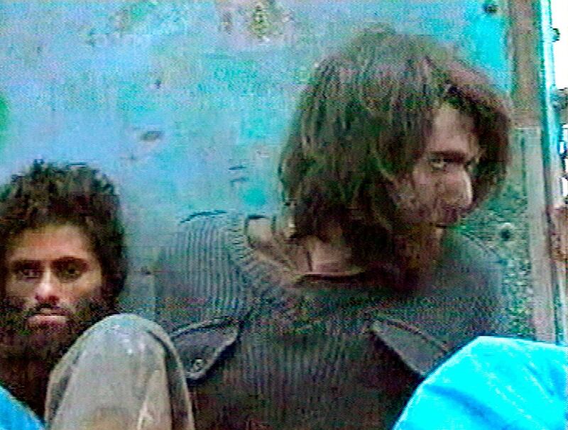 FILE - This file image taken Dec. 1, 2001, from television footage in Mazar-i-Sharif, Afghanistan, shows John Walker Lindh, right, claiming to be an American Taliban volunteer. Lindh, the young Californian who became known as the American Taliban after he was captured by U.S. forces in the invasion of Afghanistan in late 2001, is set to go free Thursday, May 23, 2019, after nearly two decades in prison.   (AP Video, File)