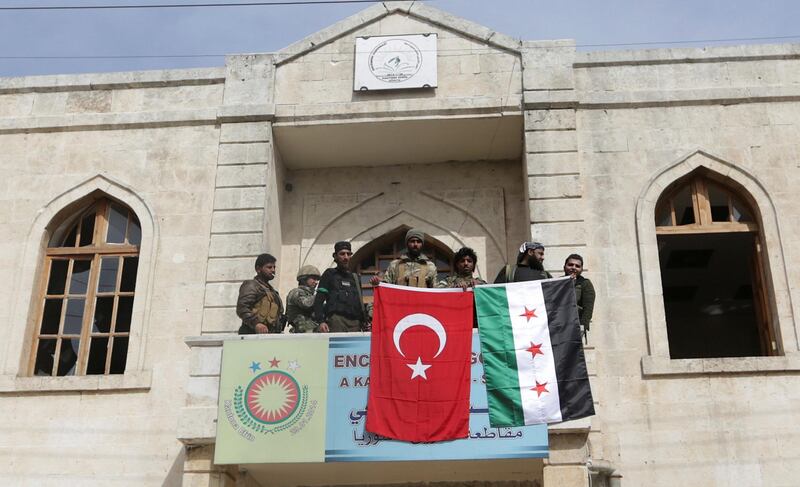 Members of Turkish forces and the Free Syrian Army pose with their flags as they are deployed in Afrin, Syria on March 18, 2018. Khalil Ashawi / Reuters
