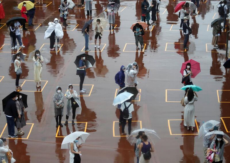 Visitors practice social distancing while waiting to enter the park in the poor weather during the reopening of Tokyo Disneyland. REUTERS