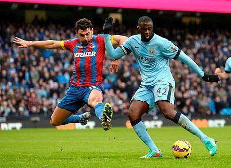 Manchester City's Ivorian midfielder Yaya Toure, right, shoots to score their third goal as Crystal Palace's Australian midfielder Mile Jedinak closes in during their English Premier League football match at the Etihad Stadium in Manchester, north west England, on December 20, 2014. AFP PHOTO / OLI SCARFF