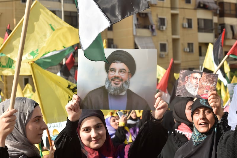 Hezbollah supporters hold up pictures of Mr Nasrallah in Beirut, ahead of his address. EPA