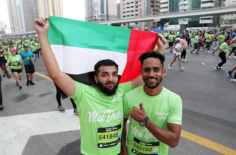 Two participants display the UAE flag during Dubai Run 2022 on Sheikh Zayed Road