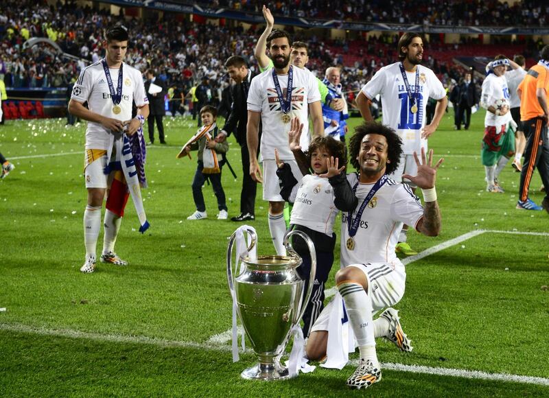 Real Madrid's Brazilian defender Marcelo (R) celebrates with the trophy at the end of the UEFA Champions League Final Real Madrid vs Atletico de Madrid at Luz stadium in Lisbon, on May 24, 2014. Real Madrid won 4-1.  AFP PHOTO/ MIGUEL RIOPA (Photo by MIGUEL RIOPA / AFP)