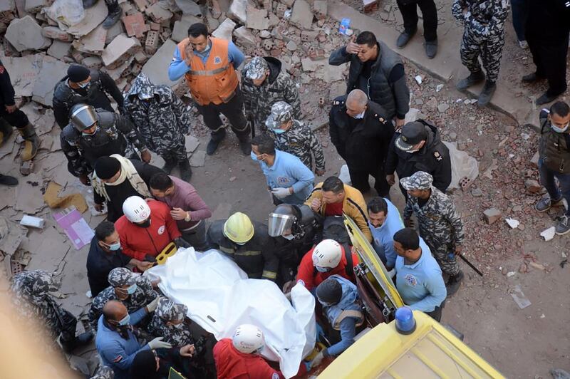 Civilians, and security forces look on as rescue workers rush a victim to an ambulance after being removed from the rubble of a building that collapsed in the Egyptian capital Cairo. AFP
