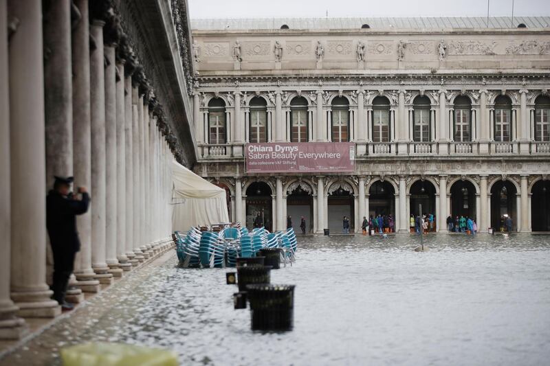 People stand beside a flooded St. Mark's Square in Venice, Italy. AP Photo