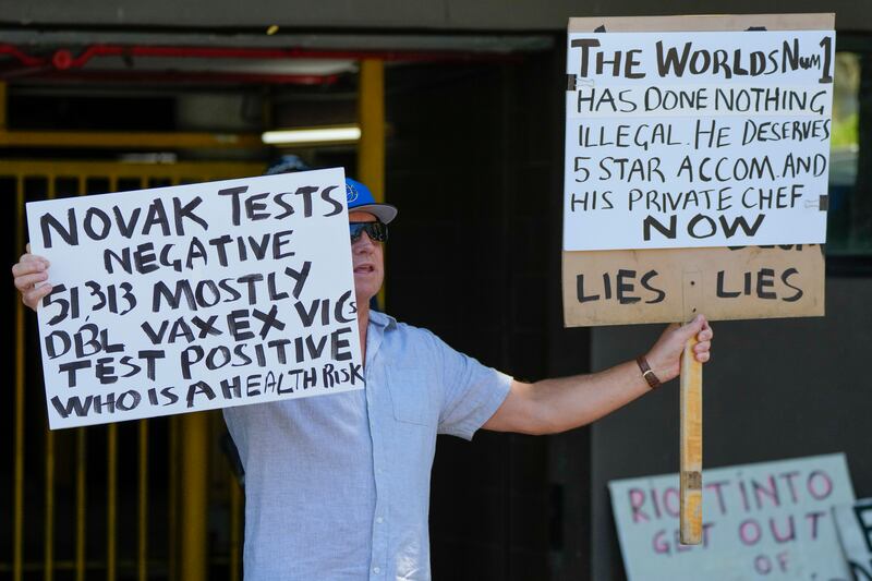 A supporter of Serbian Novak Djokovic holds placards outside an immigration detention hotel where Djokovic is confined in Melbourne. AP