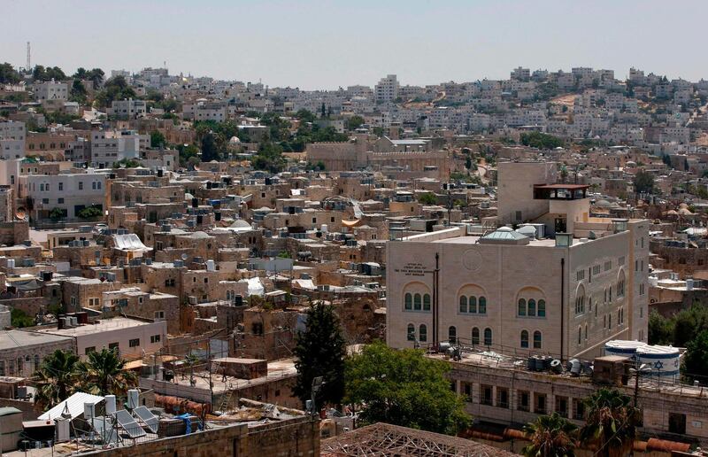 A view of the Israeli settlement point of Beit Romano in the midst of Palestinian buildings, with the Ibrahimi Mosque, also called Tomb of the Patriarchs, in the background, in the city of Hebron in the occupied West Bank.  AFP