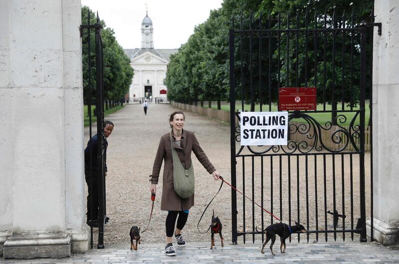 A woman with three dogs leaves the polling station at Burton Court pavilion in southwest London. AFP