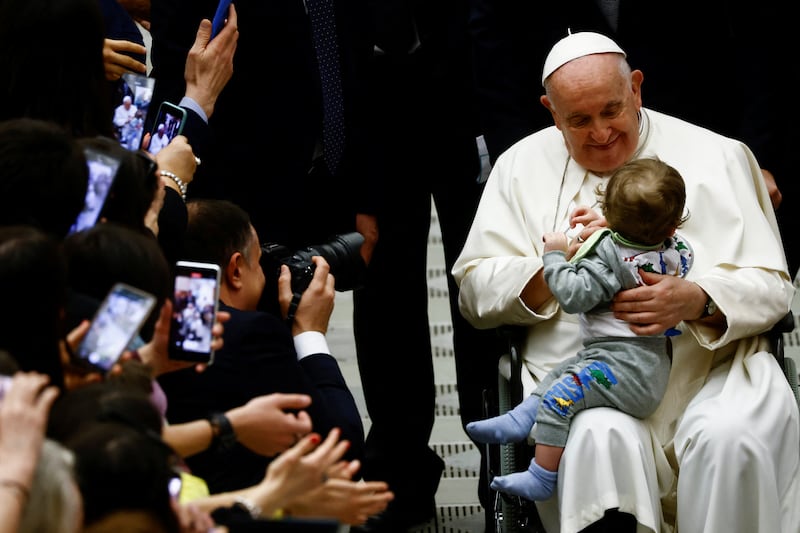 Pope Francis holds a child during a meeting with the faithful of parishes from Rho at the Vatican, March 25, 2023.  REUTERS / Yara Nardi