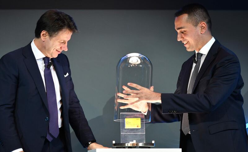 Italy Labor and Industry Minister and deputy Luigi Di Maio (R) and Italy's Prime Minister Giuseppe Conte (L) unveil the first "citizenship wage" card at the press preview of the new website and card for its new universal basic income on February 4, 2019 in Rome.  The basic income is aimed at the poorest families and job seekers, who will be offered three jobs before losing the right to the "citizenship wage".     / AFP / Alberto PIZZOLI

