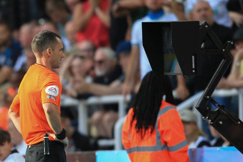 The referee consults the pitch-side monitor before reversing his red card decision. AFP