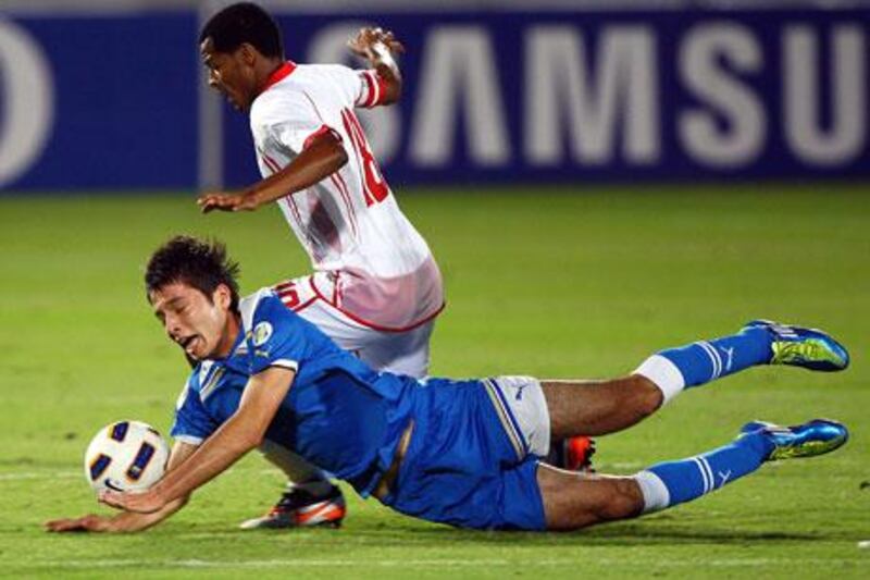 Temurkhuja Abdukholiqov, left, hit the turf, but he and his Uzbekistan teammates didn't fall to Mohamed Fawzi and the UAE on Wednesday night.