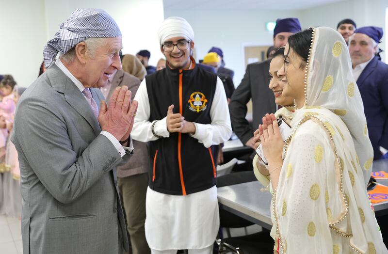 King Charles makes the traditional namaste gesture as he speaks to volunteers at Guru Nanak Gurdwara in Luton. PA