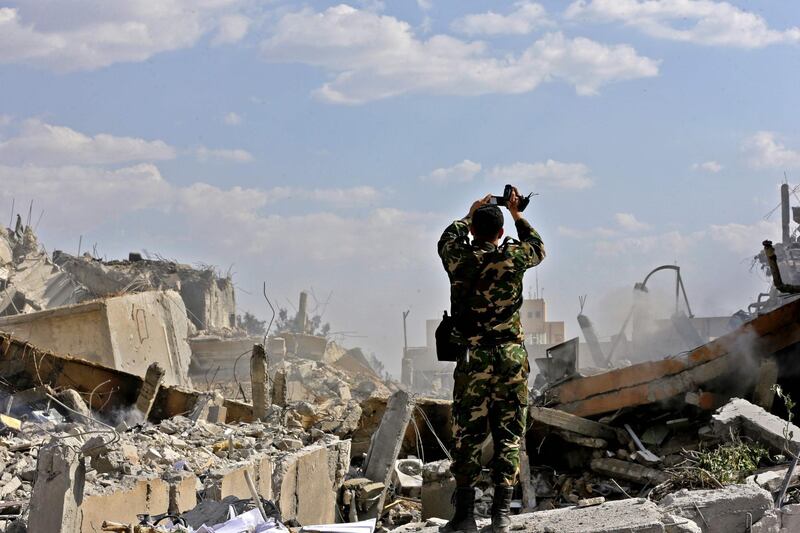 A Syrian soldier inspects the wreckage of a building described as part of the Scientific Studies and Research Centre (SSRC) compound in the Barzeh district, north of Damascus, during a press tour organised by the Syrian information ministry, on April 14, 2018.
The United States, Britain and France launched strikes against Syrian President Bashar al-Assad's regime early on April 14 in response to an alleged chemical weapons attack after mulling military action for nearly a week. Syrian state news agency SANA reported several missiles hit a research centre in Barzeh, north of Damascus, "destroying a building that included scientific labs and a training centre". / AFP PHOTO / LOUAI BESHARA