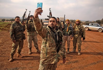 Turkish-backed Syrian fighters pose for a "selfie" photo on the phone of one of their own as they assemble in the village of Miznaz, on the eastern outskirts of Aleppo province, on February 14, 2020 as they prepare for a counter-offensive against advancing government forces in the Aleppo countryside.  / AFP / AAREF WATAD
