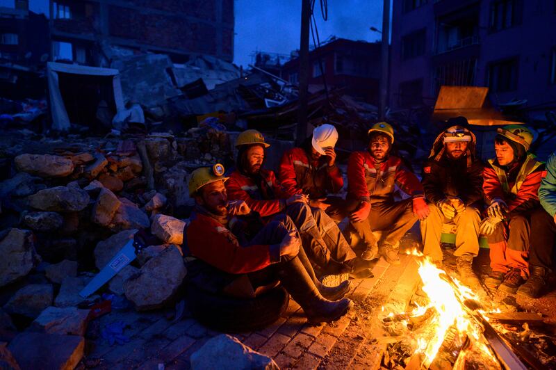 Rescuers sit by a bonfire in Hatay, Turkey. AFP