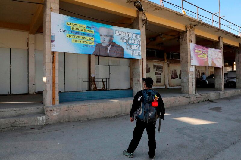 A man looks at a banner showing the portrait of late Israeli prime minister David Ben Gurion with text in Hebrew (R) reading "Rebuilding the Jewish Quarter 'The Market' in Hebron", with another on its left showing the portrait of Israeli President Reuven Rivlin, hanging on an old market building along al-Shuhada street in the flashpoint city of Hebron in the occupied West Bank, following an announcement by the new Israeli hard-right defence minister to start planning a new Jewish neighbourhood in the wholesale market complex. AFP