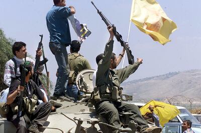 Members of Hezbollah wave their guns and flags towards Israel next to the fence that separates Lebanon from Israel in the border town of Kfar Kila, some 120 km. south of  the capital Beirut Wednesday, May 24, 2000. Israel completed overnight their withdrawal from their so called "security zone" after nearly two decades of occupation. (AP Photo/Enric Marti)