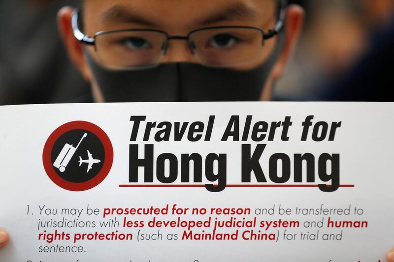 A protester holds up a banner warning of the dangers of traveling to Hong Kong at Hong Kong International Airport. AP Photo