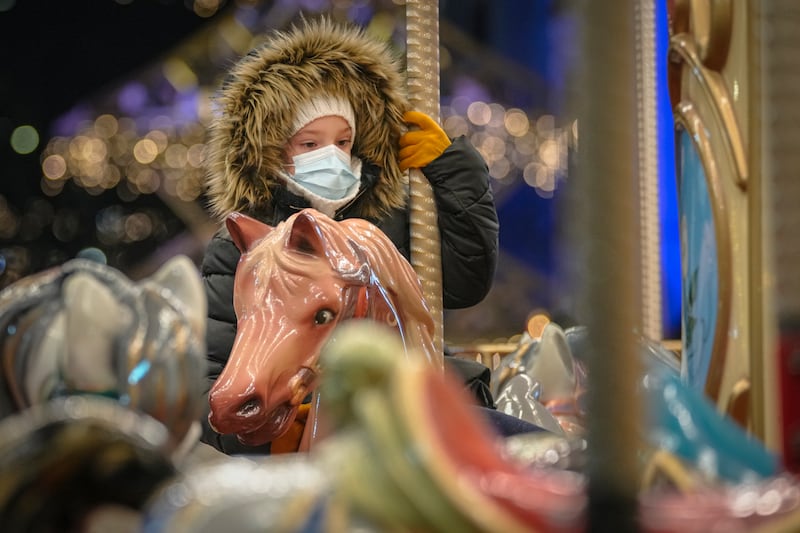 A child wearing a mask rides on a carousel at a Christmas fair in Bucharest, Romania. AP