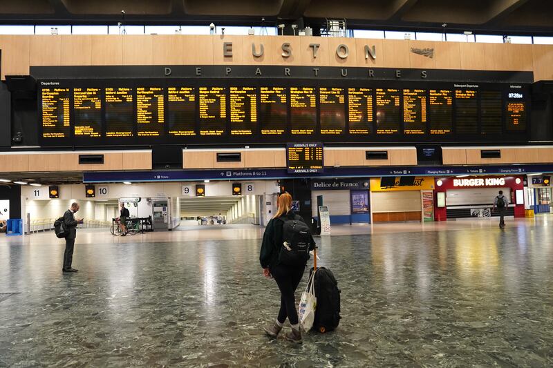 A passenger checks the departure boards at a quiet London Euston train station. PA