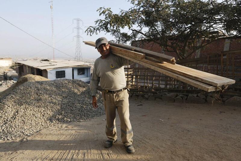Franz Moreno poses for a photograph as he carries lumber to build a third storey on his mother’s house in Gosen City. Moreno works in construction and renovation. He lived for a while in Chile, but returned to Peru as the economy improved. Mariana Bazo / Reuters