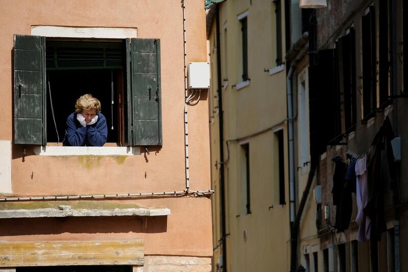 A woman looks out of an apartment window as Italians remain under lockdown to prevent the spread of the coronavirus disease (COVID-19) in Venice, Italy. REUTERS