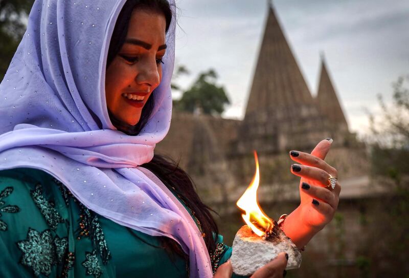 An Iraqi Yazidi woman holds a candle outside the Temple of Lalish, in a valley near the Kurdish city of Dohuk about 430 kilometres northwest of the capital Baghdad, on April 16, 2019, during a ceremony marking the Yazidi New Year. Of the 550,000 Yazidis in Iraq before the Islamic State (IS) group invaded their region in 2014, around 100,000 have emigrated abroad and 360,000 remain internally displaced. Roughly 3,300 Yazidis have returned from IS captivity in the last five years, only 10 percent of them men. / AFP / SAFIN HAMED
