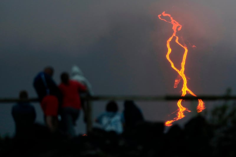 People look at lava erupting from the Piton de la Fournaise or the Peak of the Furnace flowing down the east-south-east face  on the Indian Ocean island of Reunion. AFP