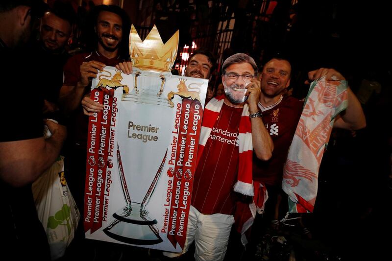 A Liverpool fan celebrates winning the Premier League with a cut out of manager Jurgen Klopp outside Anfield after Chelsea won their match against Manchester City. Reuters