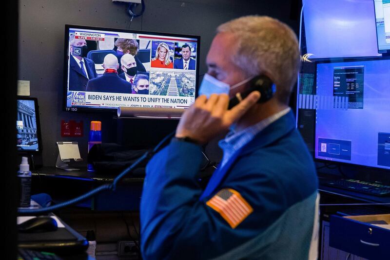 In this photo provided by the New York Stock Exchange, the presidential inaugural plays on a screen as trader Timothy Nick works in a booth on the trading floor, Wednesday, Jan. 20, 2021. U.S. stocks are rallying to records Wednesday on encouraging earnings reports and continued optimism that new leadership in Washington will mean more support for the struggling economy. (Colin Ziemer/New York Stock Exchange via AP)