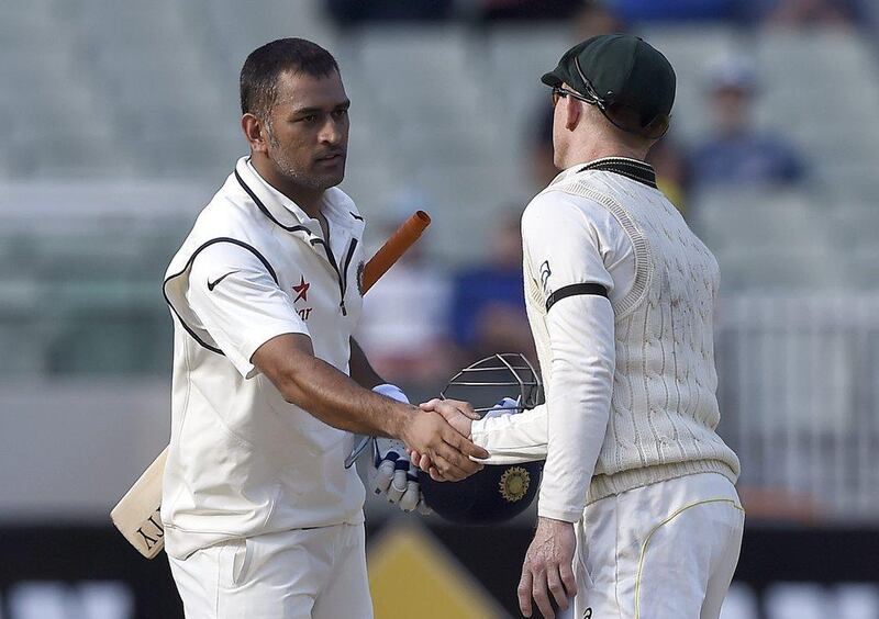 India captain MS Dhoni, left, shakes hands with Australia's Chris Rogers at the end of the final day of the third Test on Tuesday in Melbourne. Andy Brownbill / AP / December 30, 2014
