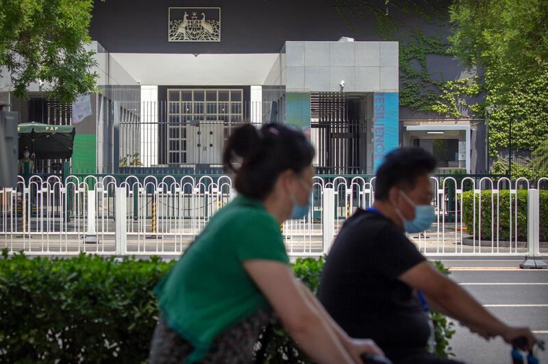 People wearing face masks to protect against the new coronavirus ride past the Australian Embassy in Beijing last week. China is advising its citizens not to visit Australia, citing racial discrimination and violence against Asians, in what appears to be Beijing's latest attempt to punish the country for advocating an investigation into the coronavirus pandemic. AP Photo