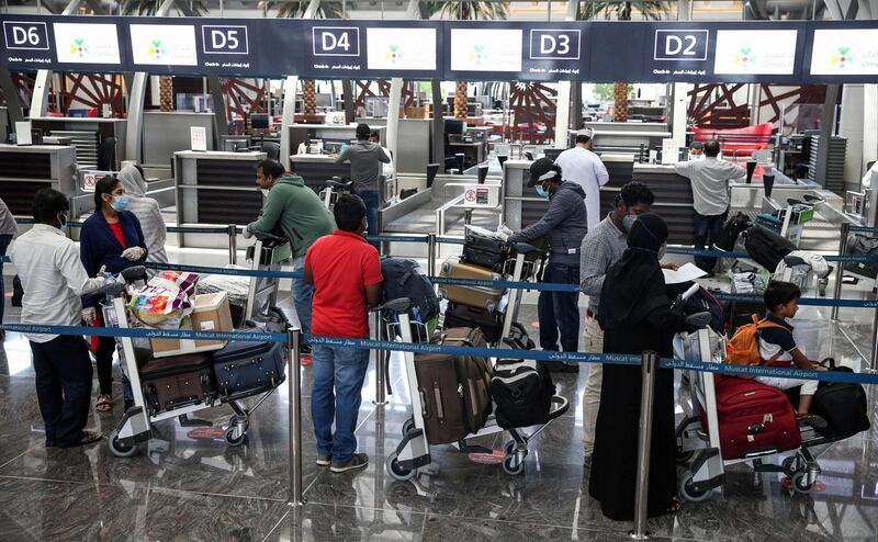 Indian nationals residing in Oman, wearing face masks due to the COVID-19 coronavirus pandemic, queue with their luggage at the check-in counter at a terminal in Muscat International Airport ahead of their repatriation flight from the Omani capital, on May 12, 2020.  / AFP / MOHAMMED MAHJOUB
