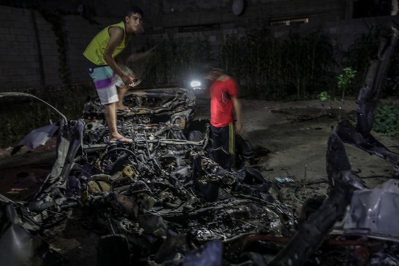 epa06814712 Palestinians inspect a destroyed car after Israeli air strike in al-Shejaeiya neighbouhood in the east Gaza City, Gaza Strip, 17 June 2018.  EPA/MOHAMMED SABER