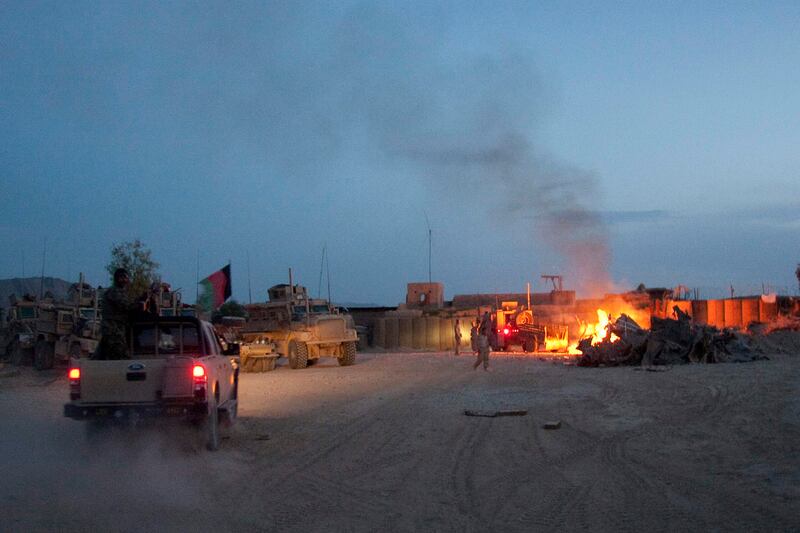An Afghan National Army pickup truck passes a fire in a trash burn pit south of Kabul, Afghanistan.  AP