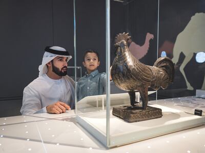 Emarati father and son in children's museum interacting with rooster
