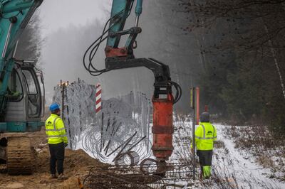 Workers build a wall along the Polish-Belarus border in Tolcze, north-eastern Poland, on January 27, 2022.  The 5. 5-metre high wall will run along 186 kilometres of the border – almost half the total length – and is to be completed in June.  AFP