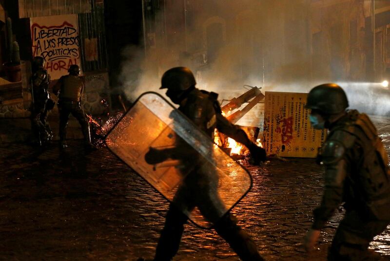 Security forces are seen near a burning barricade during a protest against the Pension Funds Administration after a congressional session on a pensions reform in Valparaiso, Chile. Reuters