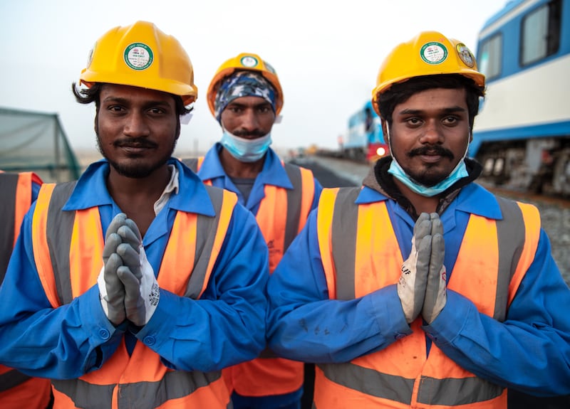 Three Etihad Rail workers take a rest, with the inspection train on right.