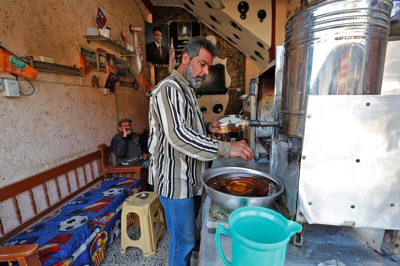A coffee shop worker pours a drink for a customer at a market in Tahrir Square, Baghdad. AFP