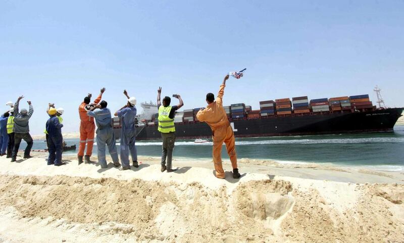 Egytpian workers wave towards a container ship sailing on the waterway of the new Suez Canal in Ismailia, Egypt.  EPA