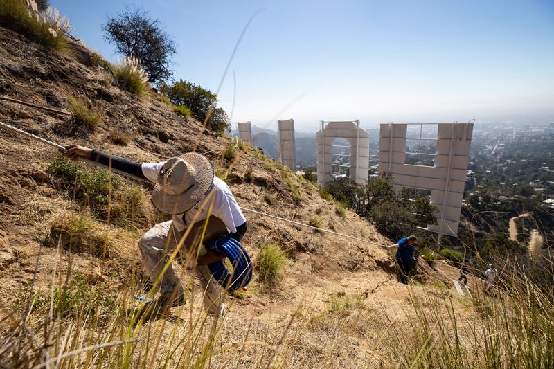 Workers use a rope to descend a steep slope as they repaint the landmark Hollywood sign in Los Angeles, California. EPA