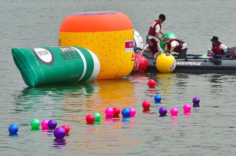 Greenpeace volunteers collect beach balls symbolising microbeads from cosmetic products on the Han river in Seoul, Korea. The microplastics have been banned in the US but there is no law governing their use in the UAE. A group of schoolgirls plan to change that. Jung Yeon-je / AFP