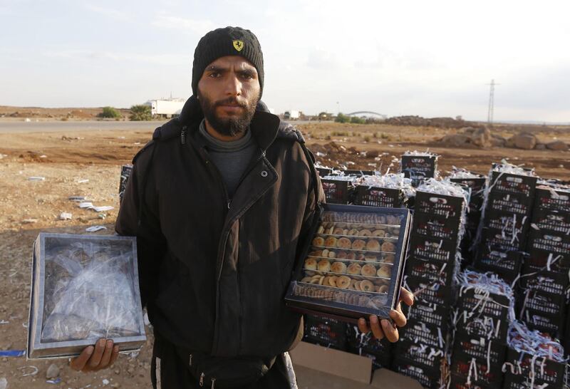 Bahaa al-Masri displays date-filled pastries and sesame biscuits he sells to Jordanians at the recently reopened Nassib border post in the Deraa province,at the Syrian-Jordanian border south of Damascus on November 7, 2018.  Syrian regime forces retook control of the Nassib border crossing from rebels in July, and last month reopened it after a three-year closure, allowing Jordanians to dash over for cheap shopping. / AFP / LOUAI BESHARA
