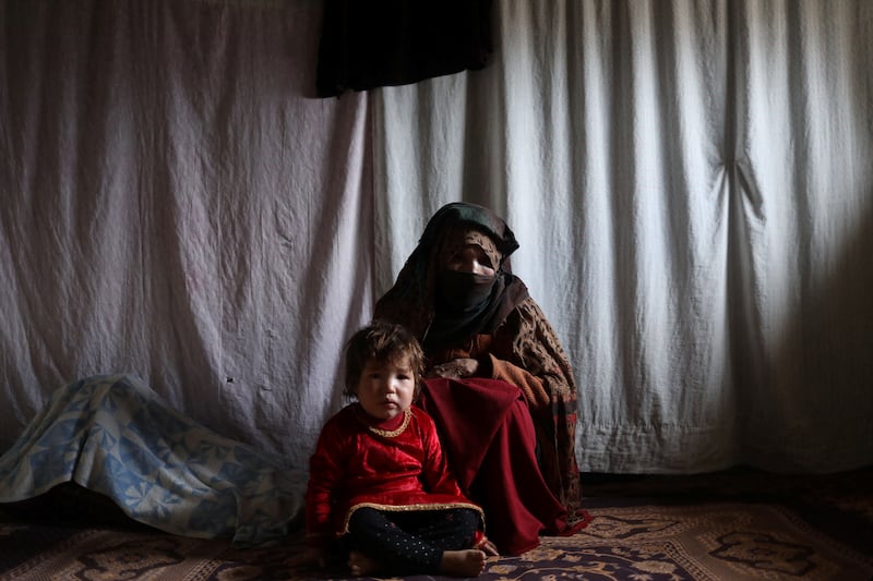 Kubra, 57, with her grandchild in a house in Bamiyan, Afghanistan, December 22, 2021. 'We got two sacks of flour last spring that we're still using. After that, we have to have faith that God will help us," Kubra says. Reuters