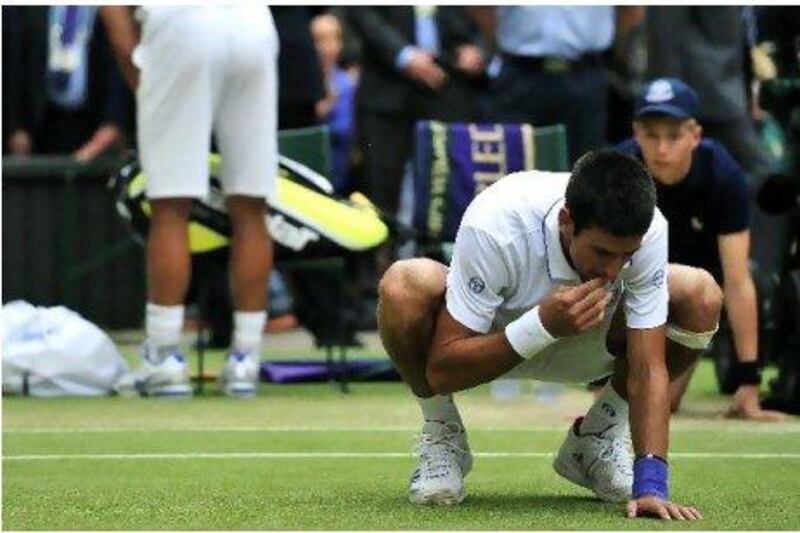 Novak Djokovic tastes the rye grass on Centre Court after his victory against Rafael Nadal on Sunday.