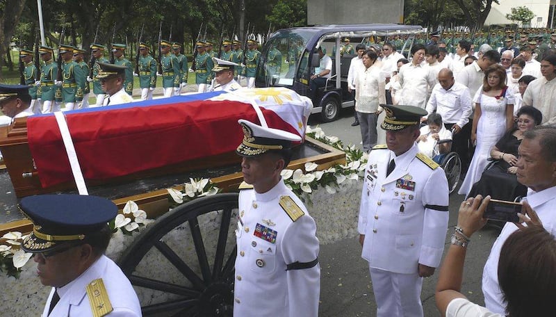 Ferdinand Marcos’ flag-draped casket is carried by horse-drawn carriage with a military escort through Taguig, Philippines, on November 18, 2016, on its way for internment in the Cemetery of Heroes, followed by the ex-dictator’s wheelchair-bound wife Imelda, 87, and their children and grandchildren. Office of Ilocos Norte Governor Imee Marcos via AP