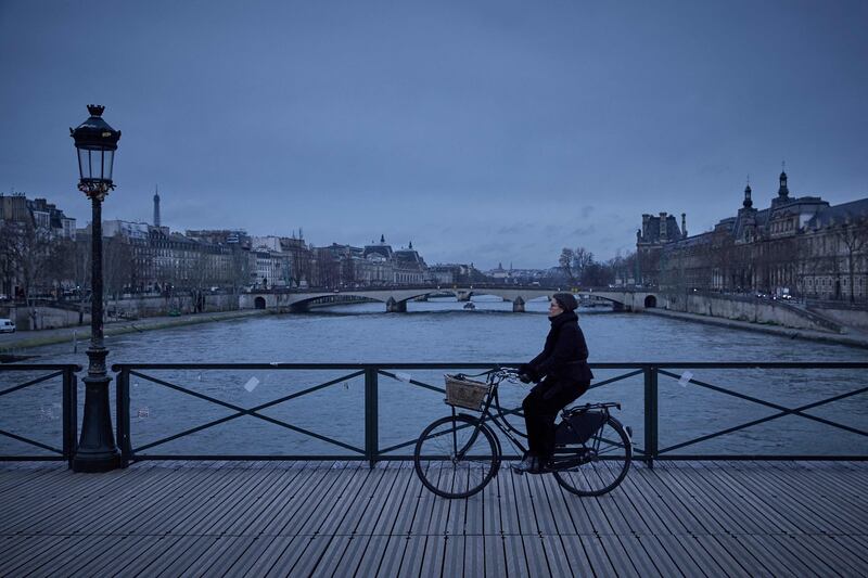 A woman rides a bike on the Pont des Arts bridge over the Seine river, in Paris. AFP
