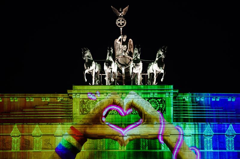 Hands forming a heart with a rainbow colored sweatband are projected on the Brandenburg Gate during the Festival of Lights in Berlin, Germany, 07 October 2022.  During the festival, buildings and landmarks of the German capital are screened with light installations and 3D projections.  The festival takes place from 07 to 16 October 2022 in 35 places showing 70 installations.   EPA / CLEMENS BILAN